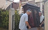 Tom Furstenberg, right, and a member of the Jewish community of Deventer carries out the Torah ark of their former synagogue, July 30, 2018. (Cnaan Liphshiz/JTA)