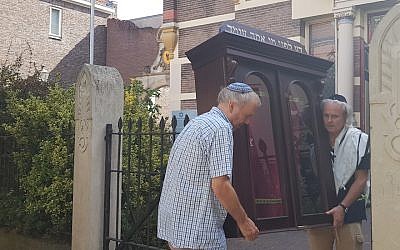 Tom Furstenberg, right, and a member of the Jewish community of Deventer carries out the Torah ark of their former synagogue, July 30, 2018. (Cnaan Liphshiz/JTA)