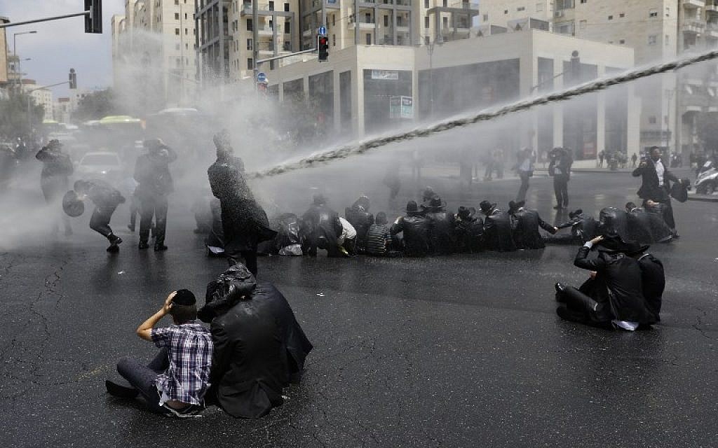 Ultra-Orthodox Jews, demonstrating at the arrest of a draft dodger, are sprayed with water cannons by Israeli security forces in Jerusalem on August 2, 2018. (AFP PHOTO / MENAHEM KAHANA)