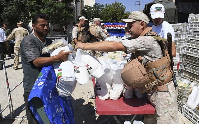 Displaced Syrians queue to receive aid, from Russia and the Chechen Ahmed Kadyrov fund, in the northern Syrian town of Tal Rifaat on August 8, 2018. (AFP/George Ourfalian)