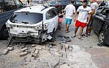People stand next to a car that was damaged after a rocket fired by terrorists from the Gaza Strip fell in the southern Israeli town of Sderot on August 9, 2018. (JACK GUEZ/AFP)