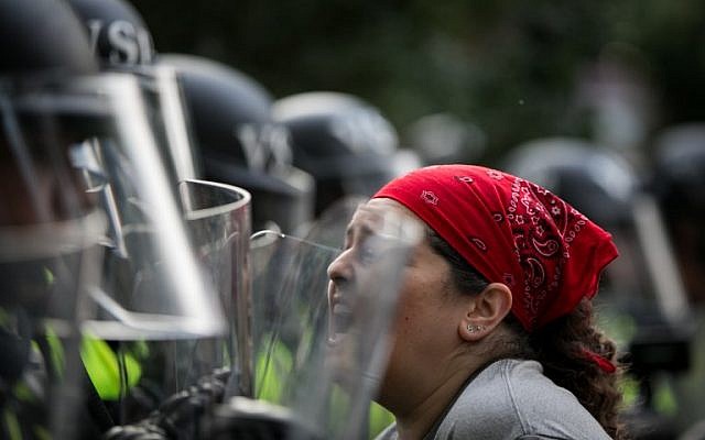 An activist confronts Virginia State Troopers in riot gear during a rally on the campus of The University of Virginia one year after the violent white nationalist rally that left one person dead and dozens injured in Charlottesville, Virginia on August 11, 2018. (AFP PHOTO / Logan Cyrus)
