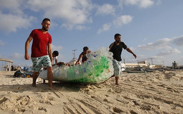 Palestinian fisherman Mouad Abu Zeid (R) and his friends carry his boat that he made of 700 Plastic empty bottles on a beach in Rafah in the southern Gaza Strip on August 14, 2018. (AFP PHOTO / SAID KHATIB) Palestinian fisherman Mouad Abu Zeid (R) and his friends carry his boat that he made of 700 Plastic empty bottles on a beach in Rafah in the southern Gaza Strip on August 14, 2018. (AFP PHOTO / SAID KHATIB)