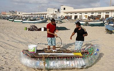 Palestinian fisherman Mouad Abu Zeid (R) and his friend work on his boat that he made of 700 Plastic empty bottles on a beach in Rafah in the southern Gaza Strip on August 14, 2018. (AFP PHOTO / SAID KHATIB)