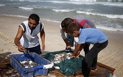 Palestinian fisherman Mouad Abu Zeid (L) shows his catch of the day on his boat that he made of 700 Plastic empty bottles on a beach in Rafah in the southern Gaza Strip on August 15, 2018. (AFP PHOTO / SAID KHATIB)