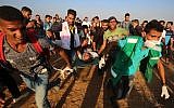 Palestinian paramedics carry an injured protester during demonstrations at the Israel-Gaza border, east of Khan Yunis in the southern Gaza Strip on August 24, 2018. (AFP/Said Khatib)