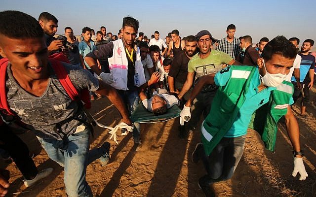 Palestinian paramedics carry an injured protester during demonstrations at the Israel-Gaza border, east of Khan Yunis in the southern Gaza Strip on August 24, 2018. (AFP/Said Khatib) Palestinian paramedics carry an injured protester during demonstrations at the Israel-Gaza border, east of Khan Yunis in the southern Gaza Strip on August 24, 2018. (AFP/Said Khatib)