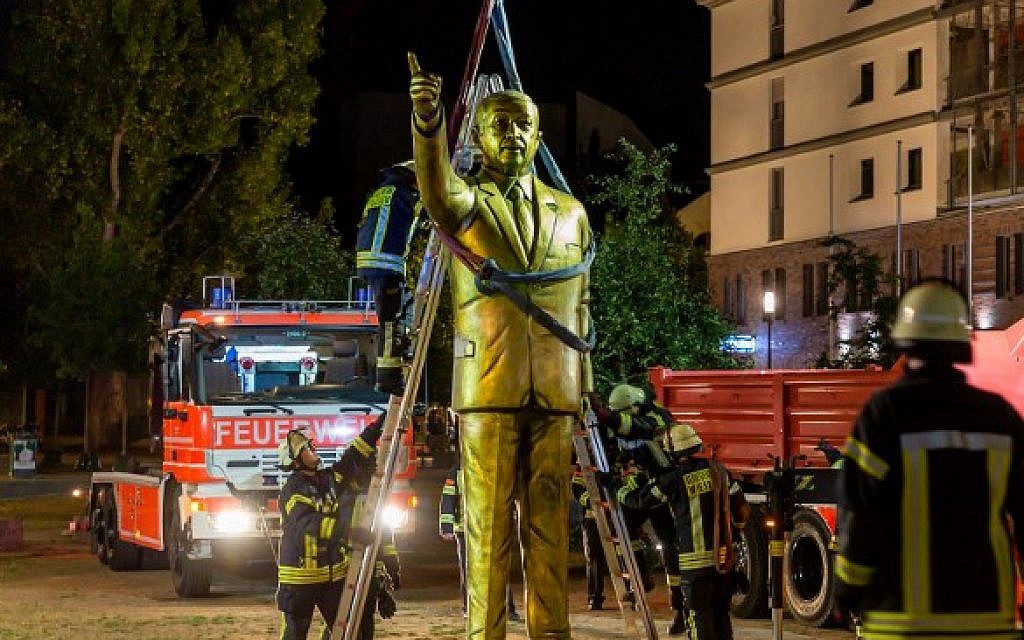 Firefighters lift a four-meter tall golden statue featuring Turkish President Recep Tayyip Erdogan to remove it on late August 28, 2018, in the western German town of Wiesbaden, where it had been placed on August 26 as part of the Biennale art festival. (AFP PHOTO / dpa / Sebastian Stenzel)