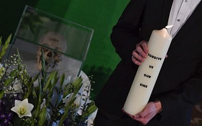 A man holds a lit candle next to one of two skulls on display during a handover ceremony of human remains taken from Namibia, in the French Church in Berlin on August 29, 2018. (AFP Photo/John Macdougall)