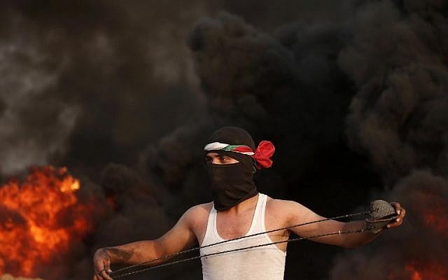 A masked Palestinian protester holding a slingshot stands by smoke rising from burning tyres during a protest near the border with Israel, east of Gaza City on August 31, 2018. (AFP PHOTO / MAHMUD HAMS) A masked Palestinian protester holding a slingshot stands by smoke rising from burning tyres during a protest near the border with Israel, east of Gaza City on August 31, 2018. (AFP PHOTO / MAHMUD HAMS)