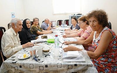 Arnold Zeligman, left, teaching Hebrew to Bella Regimov, wearing head cover, and other students at The Jewish House in Baku, Azerbaijan, July 18, 2018. (Cnaan Liphshiz/JTA)