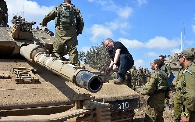 Defense Minister Avigdor Liberman climbs onto a tank in the Golan Heights on August 7, 2018. (Ariel Hermoni/Defense Ministry)
