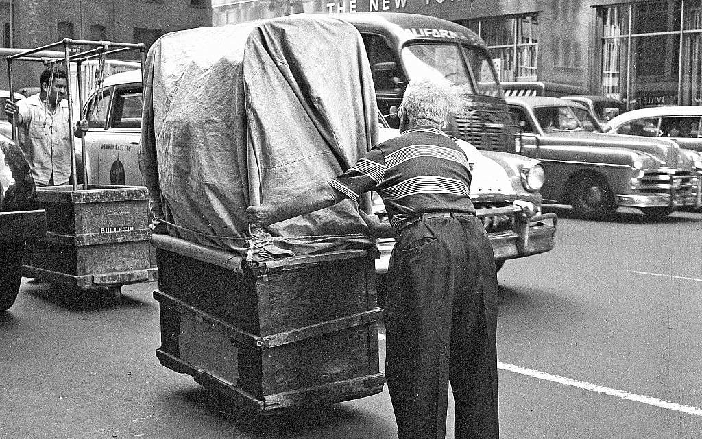 FILE - In this Aug. 26, 1958, file photo, a worker pushes a wheeled container of newly made women's wear through the streets on New York's Garment District. Hundreds of thousands of garment workers once toiled in the sweaty, elbow-to-elbow workshops of midtown Manhattan before the whirring of sewing machines was mostly silenced by foreign competition. But a group of New Yorkers - manufacturers, landlords, designers, politicians - want to preserve some of the bustling sewing scene by zoning the neighborhood for at least 300,000 square feet of garment workshops now serving higher-end designers. (AP Photo/Dan Grossi, File)