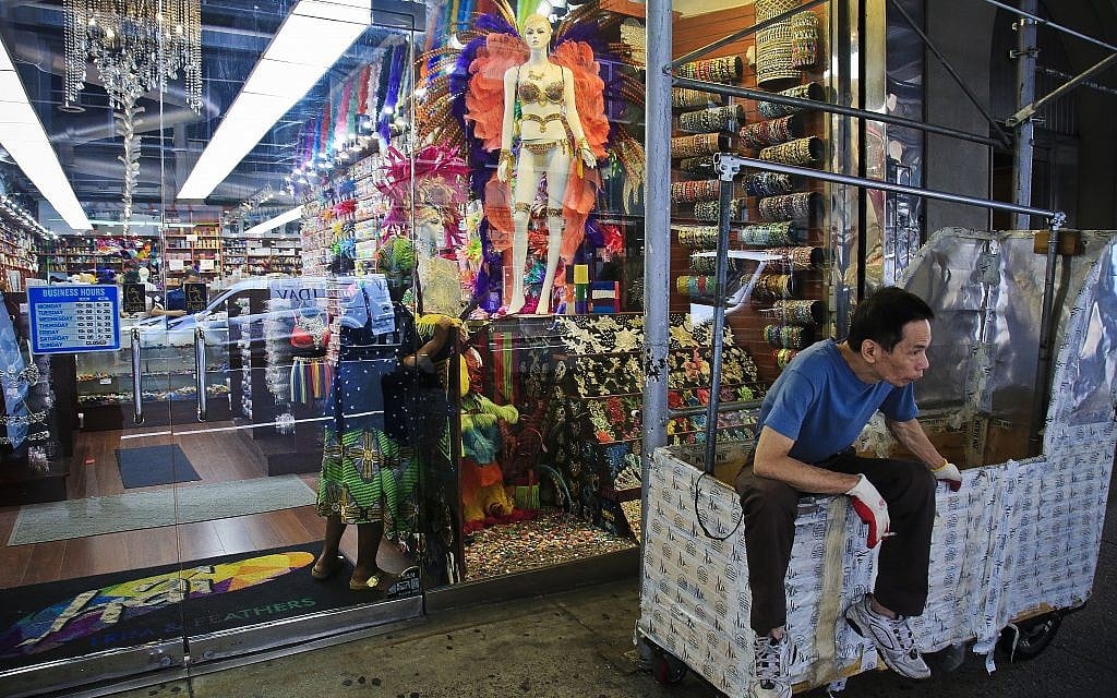 In this Aug. 1, 2018 photo, a worker rest on a clothing rack cart outside a fashion and costume accessory store in New York's Garment District. A group of manufacturers, landlords, designers and politicians has a plan to preserve a remnant of the garment industry in a neighborhood where about 5,000 people are still employed in workshops mostly serving higher-end designers. (AP Photo/Bebeto Matthews)