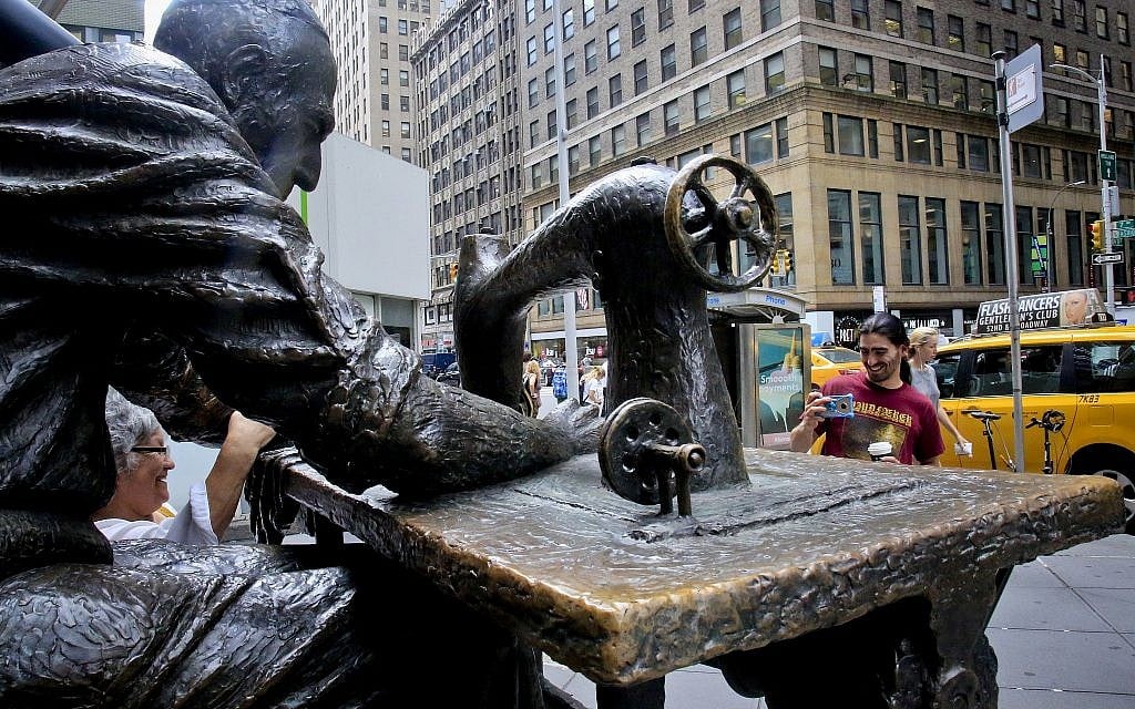 Tourists take photos at "The Garment Worker," a bronze sculpture of a garment worker wearing a yarmulke by Judith Weller at the edge of New York's Garment District, August 1, 2018. (AP Photo/Bebeto Matthews)