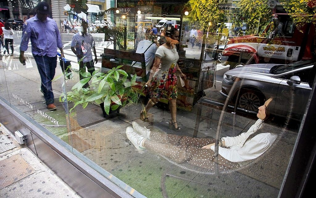 In this Aug. 1, 2018 photo, a woman rests in a hanging contour chair, right, at Nap York, a by-the-hour wellness hotel with sleeping pods in New York's Garment District. Hundreds of thousands of garment workers once toiled in the sweaty, elbow-to-elbow workshops of midtown Manhattan before the whirring of sewing machines was mostly silenced by foreign competition. (AP Photo/Bebeto Matthews)