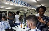 Eritrean migrant Ghrmay Negassi works at a barbershop in Tel Aviv, Israel, August 8, 2018. (Caron Creighton/AP)