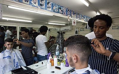 Eritrean migrant Ghrmay Negassi works at a barbershop in Tel Aviv, Israel, August 8, 2018. (Caron Creighton/AP)