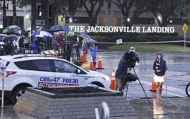 Members of the media are sheltered from the rain as they do their early morning broadcasts across the street from the Jacksonville Landing following the mass shooting that occurred there Sunday in downtown Jacksonville, Fla., August 27, 2018. (Bob Self/The Florida Times-Union via AP) Members of the media are sheltered from the rain as they do their early morning broadcasts across the street from the Jacksonville Landing following the mass shooting that occurred there Sunday in downtown Jacksonville, Fla., August 27, 2018. (Bob Self/The Florida Times-Union via AP)