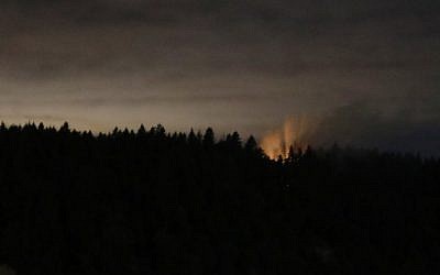 In this long-exposure photo, smoke and an orange glow are seen on Ketron Island in Washington state, early Saturday, Aug. 11, 2018 as viewed from near Steilacoom, Washington. (AP Photo/Ted S. Warren)