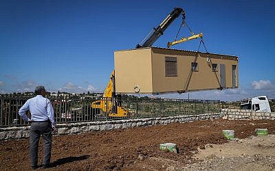 Illustrative: A crane lowers a caravan to the ground in a new settlement meant to resettle the evacuees of the illegal Netiv Ha'avot outpost in the Etzion bloc in the West Bank, on May 9, 2018. (Gershon Elinson/Flash90)