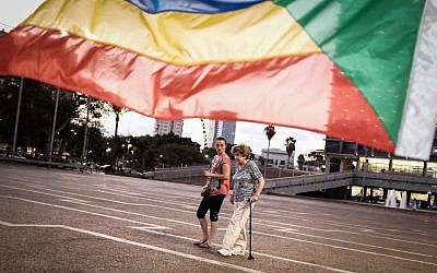 Activists and supporters of the Druze community in Israel at a protest tent against the nation-state law passed by the Knesset in July 2018, in Tel Aviv's Rabin Square on August 1, 2018. In the background is a five-colored Druze religious flag representing five wise prophets of Al-Mowahideen (Tomer Neuberg/Flash90)
