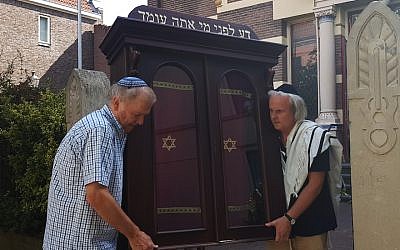 Tom Furstenberg, right, and a fellow congregant carrying the Torah ark out of the Great Synagogue of Deventer, July 30, 2018. (Cnaan Liphshiz)