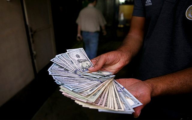 An illegal street money changer poses with his US banknotes in downtown Tehran, Iran, August 7, 2018. (AP Photo/Ebrahim Noroozi)