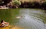 People swim in one of two freshwater pools under a large waterfall on a trail called the Upper Zavitan on July 4, 2006, at Yehudia, a park in the Golan Heights. (Phil Sussman /Flash90/File)