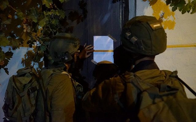 Israeli soldiers post a demolition notice on the home of a Palestinian terrorist from the West Bank village of Kobar who stabbed to death an Israeli man last month, on August 13, 2018. (Israel Defense Forces) Israeli soldiers post a demolition notice on the home of a Palestinian terrorist from the West Bank village of Kobar who stabbed to death an Israeli man last month, on August 13, 2018. (Israel Defense Forces)