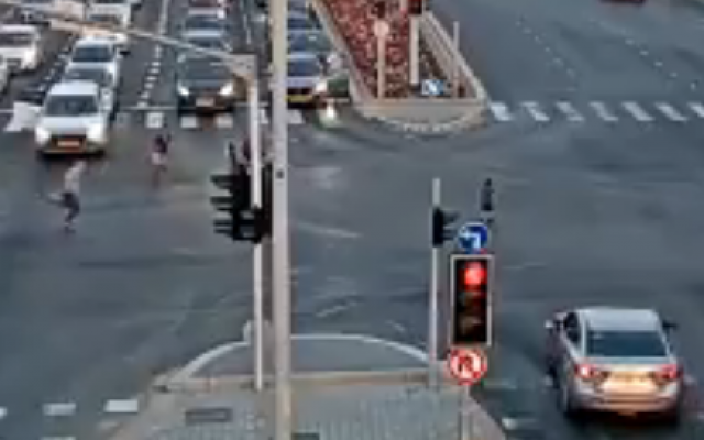Passers-by run to reach a young boy, who fell out of a car in an Ashdod intersection (security cam screenshot) Passers-by run to reach a young boy, who fell out of a car in an Ashdod intersection (security cam screenshot)