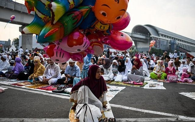 An Indonesian woman sells balloons as other gather outside a mosque before Eid al-Adha prayers in Palembang on August 22, 2018. (AFP PHOTO / MOHD RASFAN) An Indonesian woman sells balloons as other gather outside a mosque before Eid al-Adha prayers in Palembang on August 22, 2018. (AFP PHOTO / MOHD RASFAN)