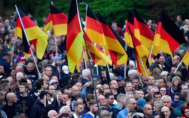 Illustrative: Demonstrators hold flags of Germany during a protest organised by the right-wing populist 'Pro Chemnitz' movement, the far-right Alternative for Germany (AfD) party and the anti-Islam Pegida movement, on September 1, 2018 in Chemnitz, eastern Germany. (AFP PHOTO / John MACDOUGALL Illustrative: Demonstrators hold flags of Germany during a protest organised by the right-wing populist 'Pro Chemnitz' movement, the far-right Alternative for Germany (AfD) party and the anti-Islam Pegida movement, on September 1, 2018 in Chemnitz, eastern Germany. (AFP PHOTO / John MACDOUGALL