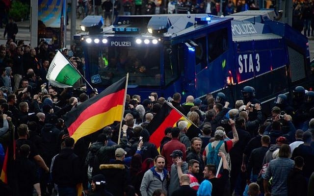 Illustrative: Demonstrators crowd around a water cannon of the police during a protest organised by the right-wing populist 'Pro Chemnitz' movement, the far-right Alternative for Germany (AfD) party and the anti-Islam Pegida movement, on September 1, 2018 in Chemnitz, eastern Germany. (AFP/John MacDougall) Illustrative: Demonstrators crowd around a water cannon of the police during a protest organised by the right-wing populist 'Pro Chemnitz' movement, the far-right Alternative for Germany (AfD) party and the anti-Islam Pegida movement, on September 1, 2018 in Chemnitz, eastern Germany. (AFP/John MacDougall)