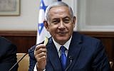 Prime Minister Benjamin Netanyahu holds a piece of fruit as he attends the weekly cabinet meeting at the Prime Minister's Office in Jerusalem September 5, 2018. (Ronen Zvulun/AFP)
