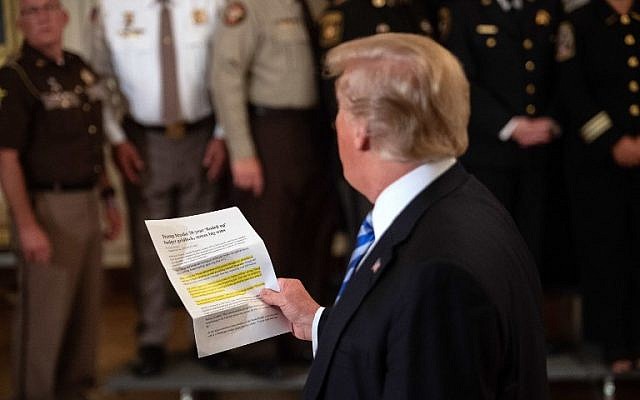 US President Donald Trump reads from an article praising his administration as he answers a journalist during a meeting with sheriffs at the White House in Washington, DC, on September 5, 2018.
Trump was responding to an anonymous "senior official" who wrote an op-ed article entitled "I Am Part of the Resistance Inside the Trump Administration" in The New York Times on September 5. (AFP PHOTO / NICHOLAS KAMM) US President Donald Trump reads from an article praising his administration as he answers a journalist during a meeting with sheriffs at the White House in Washington, DC, on September 5, 2018.
Trump was responding to an anonymous "senior official" who wrote an op-ed article entitled "I Am Part of the Resistance Inside the Trump Administration" in The New York Times on September 5. (AFP PHOTO / NICHOLAS KAMM)