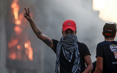 An Iraqi protester flashes the victory gesture outside outside the burning local government headquarters in the southern city of Basra on September 7, 2018 during demonstrations over poor public services. (AFP Photo/Haidar Mohammed Ali)