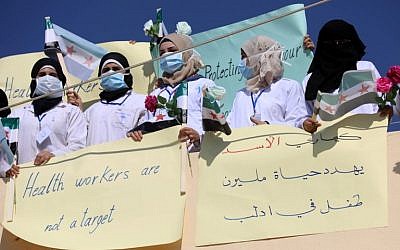 Syrian health sector workers hold banners during a rally in the village of Atmeh in the northern Idlib province, demanding that hospitals be protected in the case of an upcoming  offensive, on September 16, 2018 (AFP PHOTO / OMAR HAJ KADOUR)