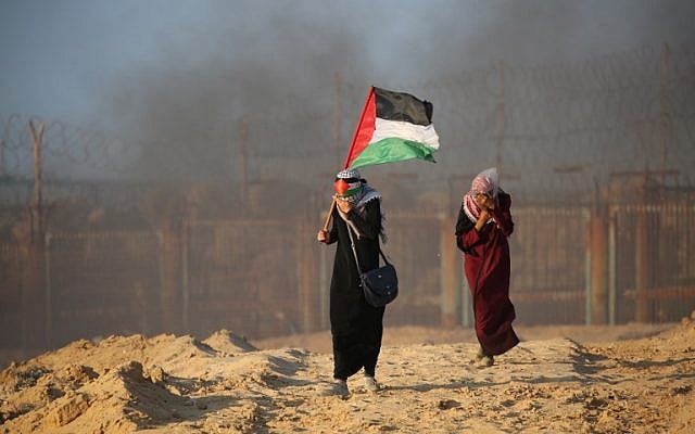 A Palestinian woman carries her national flag during a protest for lifting the Israeli blockade on Gaza on a beach in Beit Lahia near the maritime border with Israel, on September 17, 2018. (AFP/Said Khatib) A Palestinian woman carries her national flag during a protest for lifting the Israeli blockade on Gaza on a beach in Beit Lahia near the maritime border with Israel, on September 17, 2018. (AFP/Said Khatib)