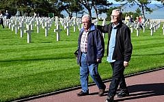 Andre Gantois (L), 72, a resident of Ludres, in eastern France, and Allen Henderson, 65, of Greenville, South Carolina, walk past graves at the Normandy American Cemetery and Memorial on September 24, 2018, in Colleville-sur-Mer. (AFP PHOTO / Damien MEYER)