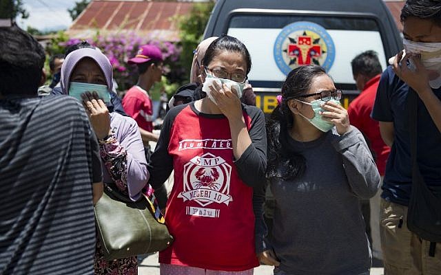 People wear masks as they attempt to identify the bodies of their relatives at the compounds of a police hospital in Palu, Indonesia's Central Sulawesi on September 30, 2018, following a strong earthquake in the area.( AFP PHOTO / BAY ISMOYO) People wear masks as they attempt to identify the bodies of their relatives at the compounds of a police hospital in Palu, Indonesia's Central Sulawesi on September 30, 2018, following a strong earthquake in the area.( AFP PHOTO / BAY ISMOYO)