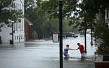 Shianne Coleman (L) gets a hand from friend Austin Gremmel as they walk in flooded streets as the Neuse River begins to flood its banks during Hurricane Florence September 13, 2018 in New Bern, North Carolina.(Chip Somodevilla/Getty Images/AFP
