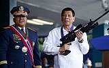 Philippine President Rodrigo Duterte, right, jokes to photographers as he holds an Israeli-made Galil rifle which was presented to him by former Philippine National Police Chief Director General Ronald "Bato" Dela Rosa at the turnover-of-command ceremony at the Camp Crame in Quezon city northeast of Manila, April 19, 2018. (Bullit Marquez/AP)