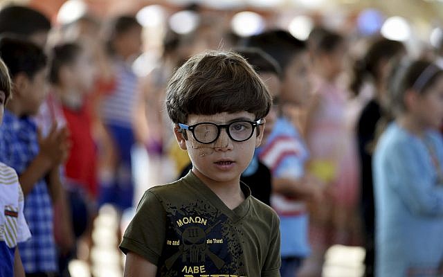In this Tuesday, September 11, 2018 photo, Muhammed Halife, 5, who was injured during a bombing, stands at his school in the northern town of Jisr al-Shughur, Syria, west of the city of Idlib. (Ugur Can/DHA via AP)