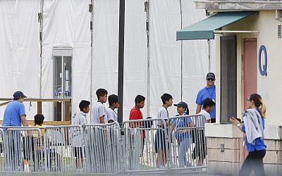 In this June 20, 2018, photo, Immigrant children walk in a line outside the Homestead Temporary Shelter for Unaccompanied Children a former Job Corps site that now houses them in Homestead, Florida. (AP Photo/Brynn Anderson)