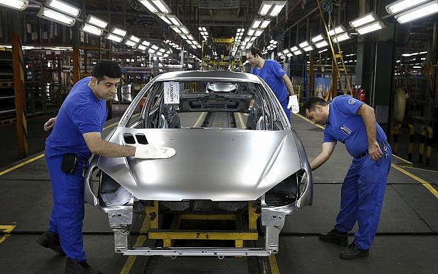 In this Sunday, September 9, 2018 photo, workers wipe the body of a car at the Iran Khodro automobile manufacturing plant just outside Tehran, Iran. (AP Photo/Ebrahim Noroozi)