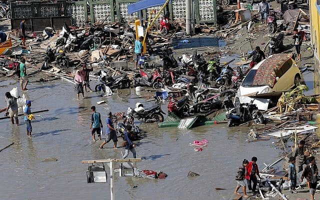 People outside a shopping mall damaged in earthquakes and a tsunami in Palu, Central Sulawesi, Indonesia, Sunday, Sept. 30, 2018. (AP Photo/Tatan Syuflana)