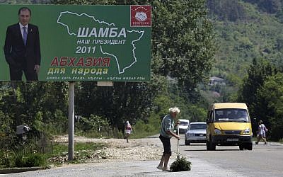 A man sweeps the road near a poster of one of three presidential candidates Sergei Shamba's in Sukhumi capital of Georgian breakaway region of Abkhazia, Wednesday, August 24, 2011. (AP/Mikhail Metzel)