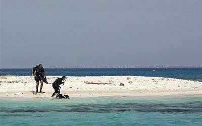 In this March 7, 2018 photo, Nouf Alosaimi, a 29-year-old female Saudi dive instructor, right, and Tamer Nasr, an Egyptian diving instructor explore a sandy island in the Red Sea after a dive, near King Abdullah Economic City, Saudi Arabia. Saudi has the longest coastline of any country along the Red Sea, and the kingdom's nascent tourism industry is betting on the clear, blue waters, coral reefs and idyllic islands off its western coastline to lure visitors from around the world. (AP Photo/Amr Nabil)
