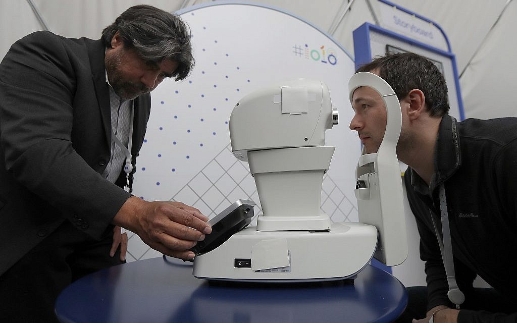 Jorge Cuadros, left, gives a demonstration of a robotic retinal camera to a reporter at the Google I/O conference in Mountain View, California, on May 8, 2018 (AP Photo/Jeff Chiu) Jorge Cuadros, left, gives a demonstration of a robotic retinal camera to a reporter at the Google I/O conference in Mountain View, California, on May 8, 2018 (AP Photo/Jeff Chiu)
